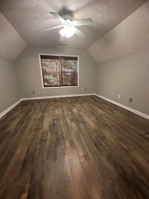 1732 Wyntercreek Ln, Hoschton, GA 30548 - additional living space featuring vaulted ceiling, dark wood-style flooring, a textured ceiling, and baseboards