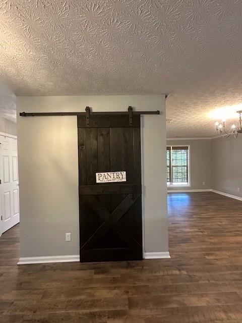 1732 Wyntercreek Ln, Hoschton, GA 30548 - interior space featuring a textured ceiling, a barn door, baseboards, and dark wood finished floors