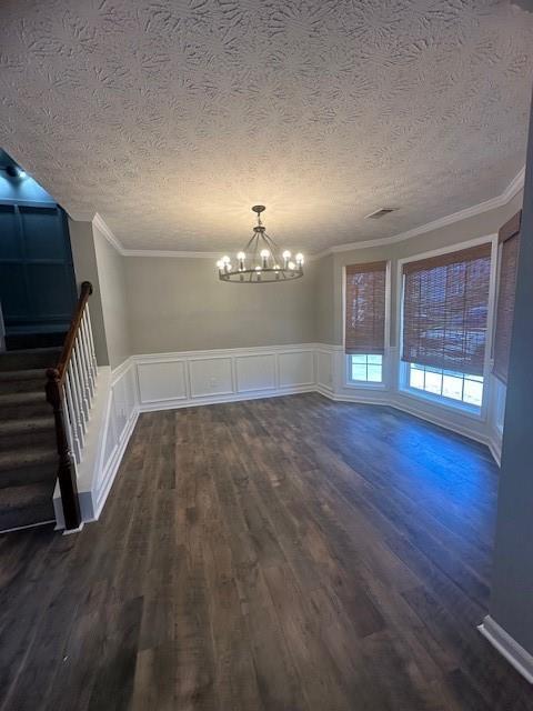 1732 Wyntercreek Ln, Hoschton, GA 30548 - unfurnished dining area featuring a notable chandelier, a textured ceiling, ornamental molding, dark wood finished floors, and stairway