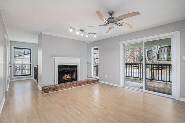 unfurnished living room with ceiling fan, a fireplace, and light wood-type flooring