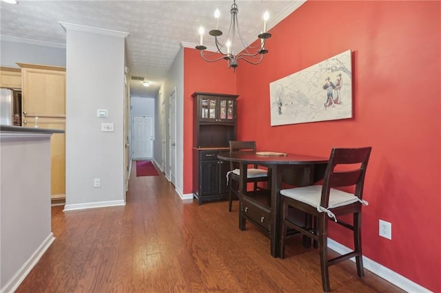 dining room with a chandelier, ornamental molding, a textured ceiling, and dark wood-type flooring