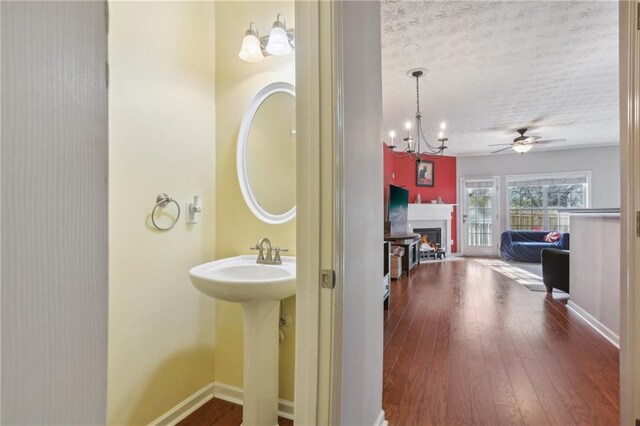 bathroom with hardwood / wood-style flooring, ceiling fan with notable chandelier, sink, and a textured ceiling