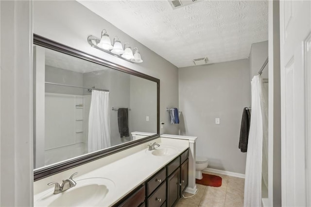 bathroom with tile patterned floors, vanity, a textured ceiling, and toilet