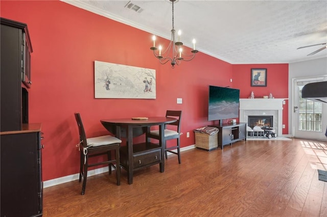 dining space featuring ceiling fan with notable chandelier, dark hardwood / wood-style flooring, and crown molding