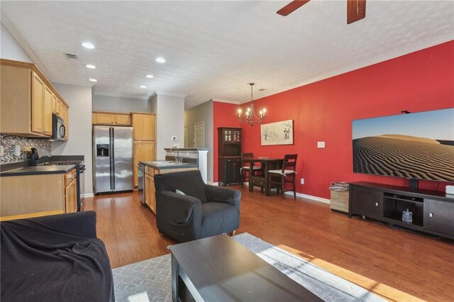 living room featuring ceiling fan with notable chandelier, hardwood / wood-style flooring, ornamental molding, and sink