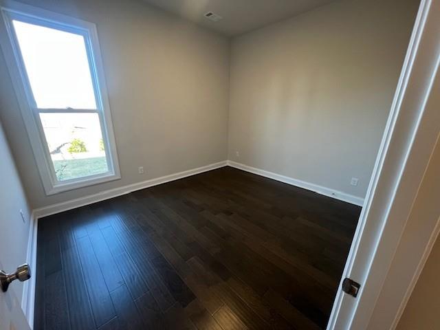 unfurnished room with dark wood-style flooring and baseboards