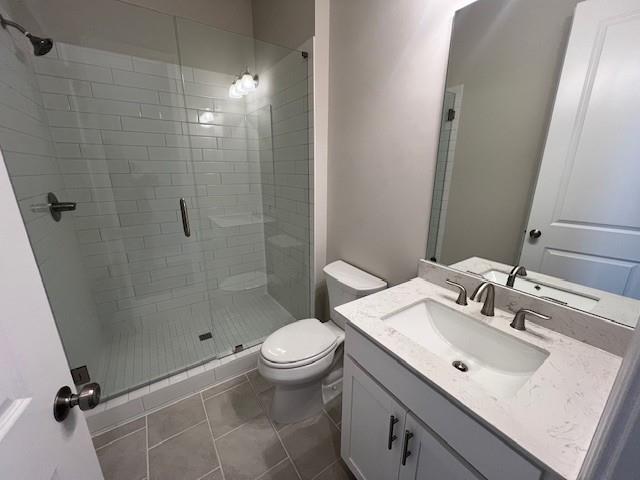 full bathroom featuring vanity, tile patterned floors, a stall shower, and toilet