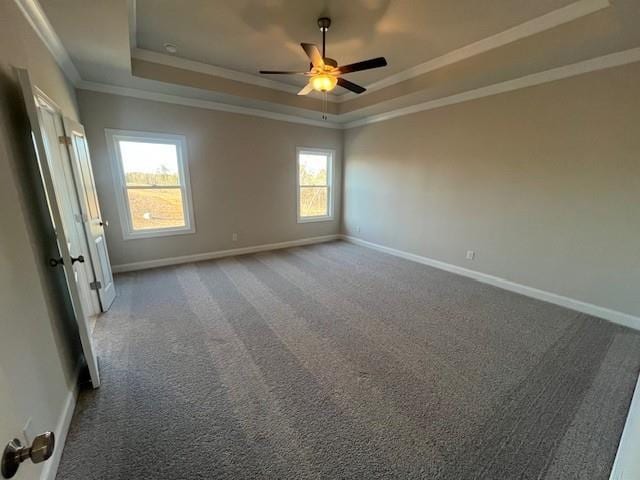 carpeted empty room with crown molding, baseboards, ceiling fan, and a raised ceiling