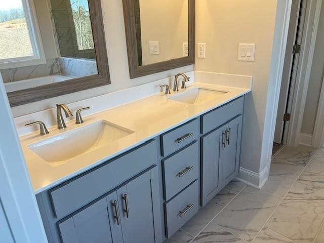 bathroom featuring a sink, baseboards, double vanity, and marble finish floor