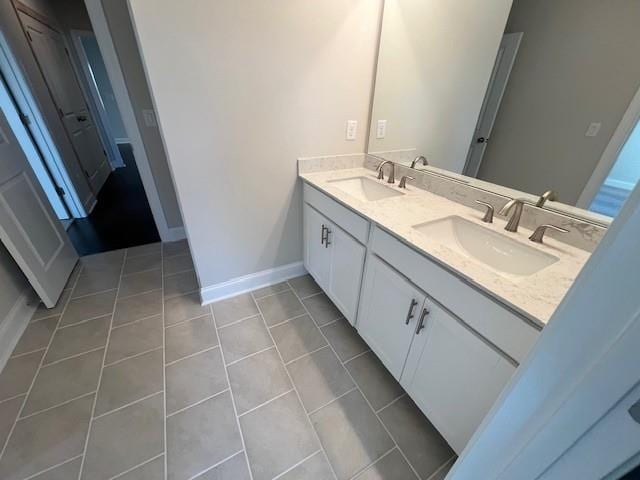 bathroom with double vanity, baseboards, a sink, and tile patterned flooring