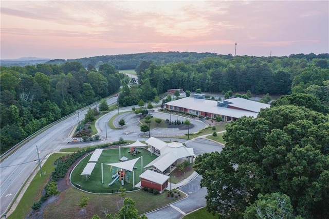 aerial view at dusk featuring a forest view