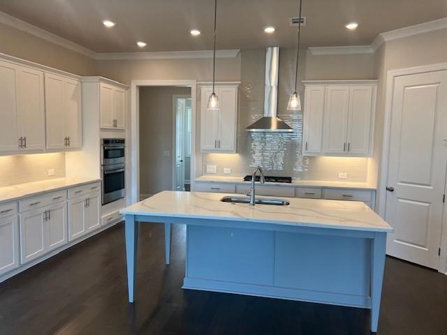 kitchen with wall chimney range hood, crown molding, stainless steel double oven, and a sink