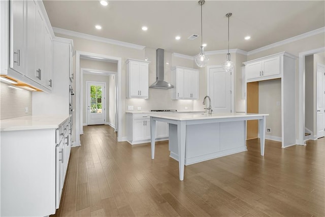 636 Silva St, Cumming, GA 30040 - kitchen with wall chimney exhaust hood, a sink, crown molding, wood finished floors, and an island with sink