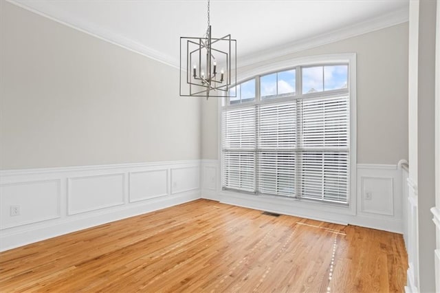 unfurnished room featuring crown molding, light hardwood / wood-style flooring, and a notable chandelier