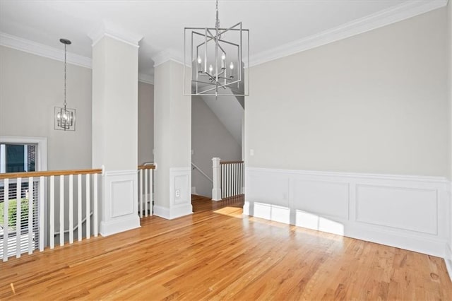 unfurnished dining area with crown molding, vaulted ceiling, wood-type flooring, and a chandelier