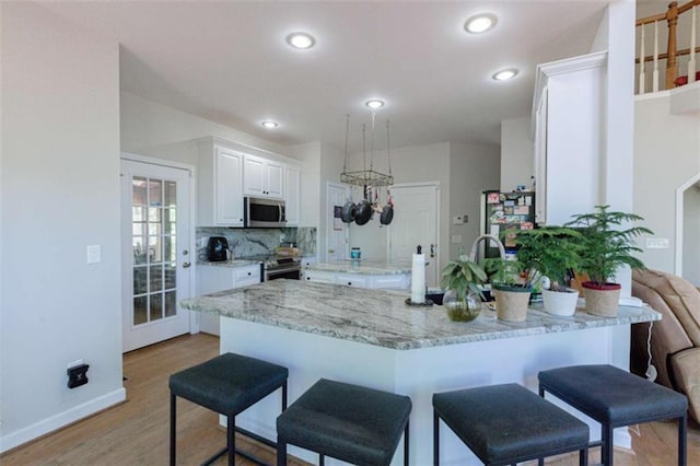 516 Turner Rd, Concord, GA 30206 - kitchen featuring stainless steel appliances, white cabinets, a breakfast bar, light wood-style floors, and recessed lighting