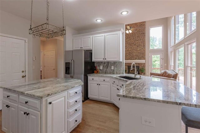 516 Turner Rd, Concord, GA 30206 - kitchen featuring a sink, a peninsula, white cabinets, stainless steel fridge, and light stone countertops