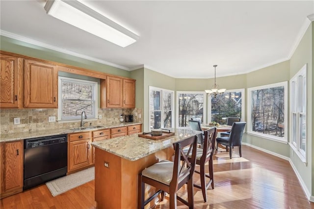 kitchen featuring decorative light fixtures, a notable chandelier, a kitchen island, sink, and black dishwasher