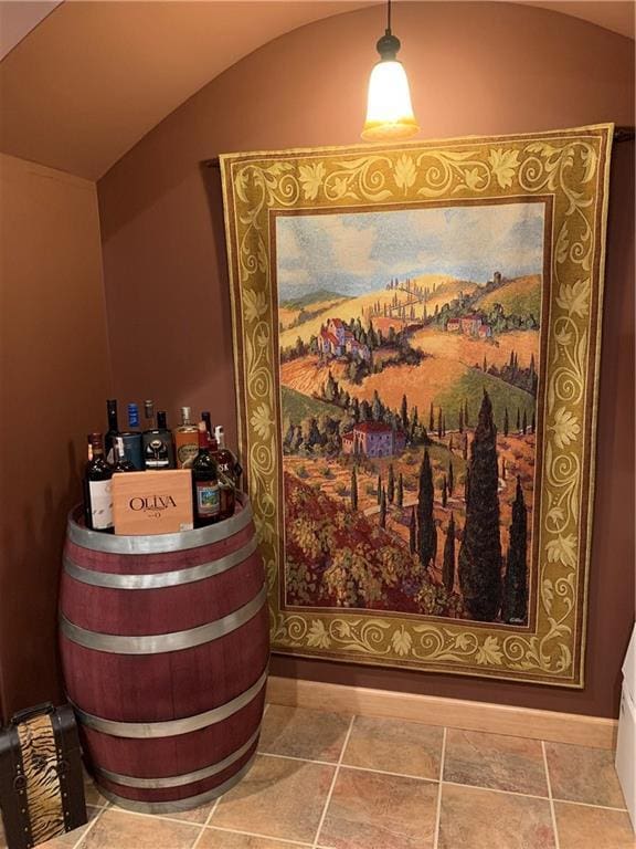 wine room featuring tile patterned flooring, lofted ceiling, and bar area