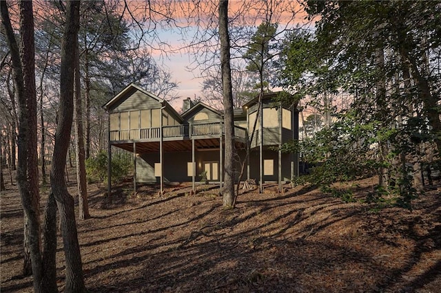 back house at dusk featuring a wooden deck