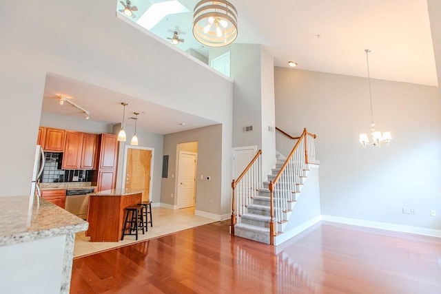 kitchen with brown cabinetry, visible vents, baseboards, light wood-style flooring, and stainless steel dishwasher