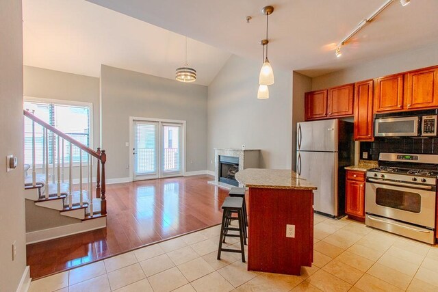 799 Hammond Dr Unit 406, Atlanta, GA 30328 - kitchen with a kitchen island, tasteful backsplash, appliances with stainless steel finishes, light tile patterned flooring, and a fireplace