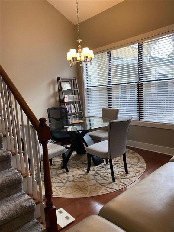 799 Hammond Dr Unit 406, Atlanta, GA 30328 - dining room featuring a chandelier, stairway, lofted ceiling, and wood finished floors