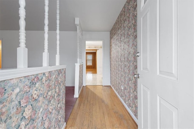 hall with baseboards, wood finished floors, and wallpapered walls