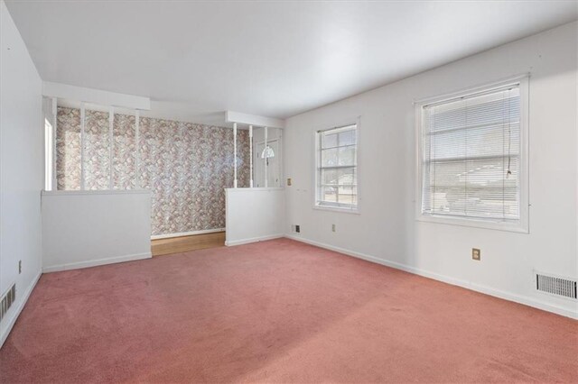 spare room featuring carpet floors, baseboards, and visible vents