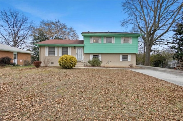 split level home featuring brick siding, fence, and concrete driveway