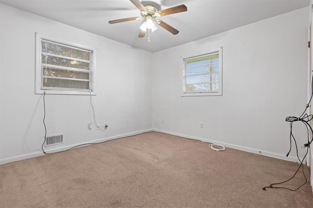 carpeted spare room featuring visible vents, baseboards, and ceiling fan