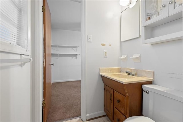 bathroom featuring toilet, baseboards, and vanity