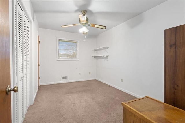 unfurnished bedroom with baseboards, a ceiling fan, carpet, and visible vents