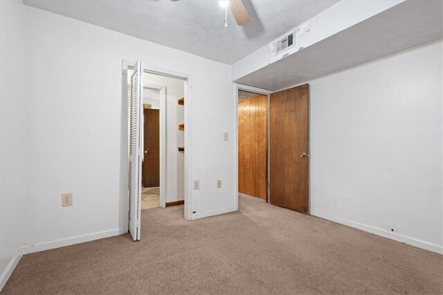 unfurnished bedroom with carpet floors, a ceiling fan, baseboards, and visible vents