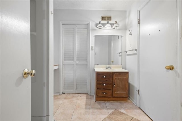 bathroom with visible vents, a closet, vanity, baseboards, and tile patterned floors