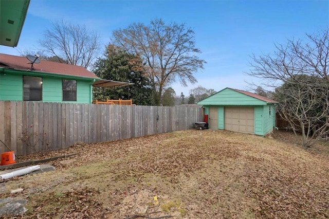 view of yard featuring a garage, fence, and an outbuilding
