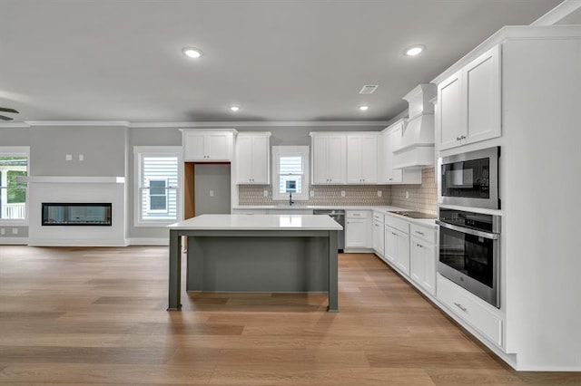 231 E Marable St, Monroe, GA 30655 - kitchen with appliances with stainless steel finishes, premium range hood, a center island, ornamental molding, and light countertops