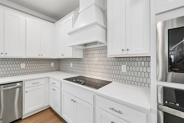 231 E Marable St, Monroe, GA 30655 - kitchen with appliances with stainless steel finishes, custom range hood, light countertops, and white cabinets