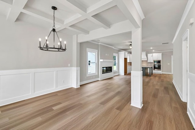 231 E Marable St, Monroe, GA 30655 - unfurnished living room featuring coffered ceiling, a ceiling fan, a chandelier, beam ceiling, and light wood-type flooring