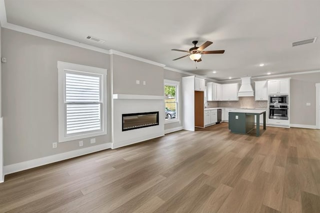 231 E Marable St, Monroe, GA 30655 - unfurnished living room with a ceiling fan, a glass covered fireplace, light wood-type flooring, crown molding, and baseboards