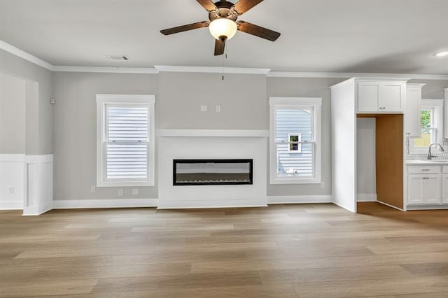 231 E Marable St, Monroe, GA 30655 - unfurnished living room with ceiling fan, light wood-style floors, crown molding, a glass covered fireplace, and a sink