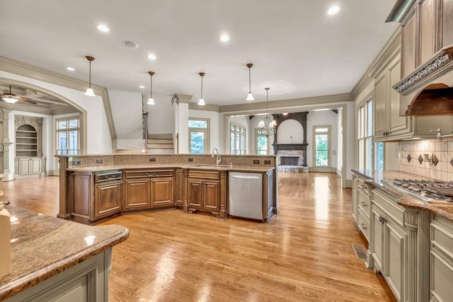 9145 Greenway Ct, Gainesville, GA 30506 - kitchen featuring appliances with stainless steel finishes, a stone fireplace, ornamental molding, brown cabinets, and light wood-style flooring