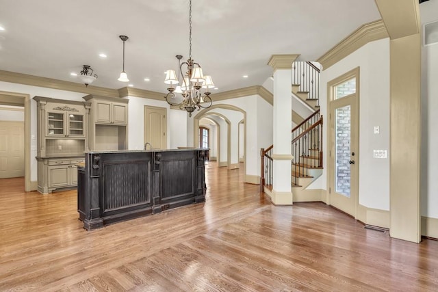 9145 Greenway Ct, Gainesville, GA 30506 - kitchen with arched walkways, ornamental molding, light wood-type flooring, cream cabinetry, and an island with sink