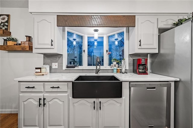 kitchen with light stone counters, white cabinetry, a sink, and stainless steel dishwasher