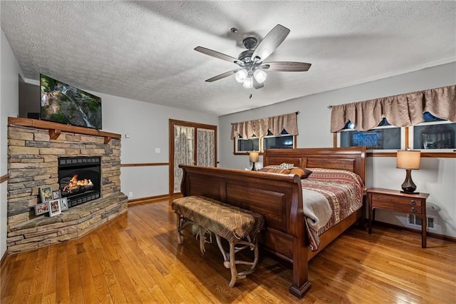 bedroom featuring visible vents, a textured ceiling, a fireplace, and light wood-style flooring