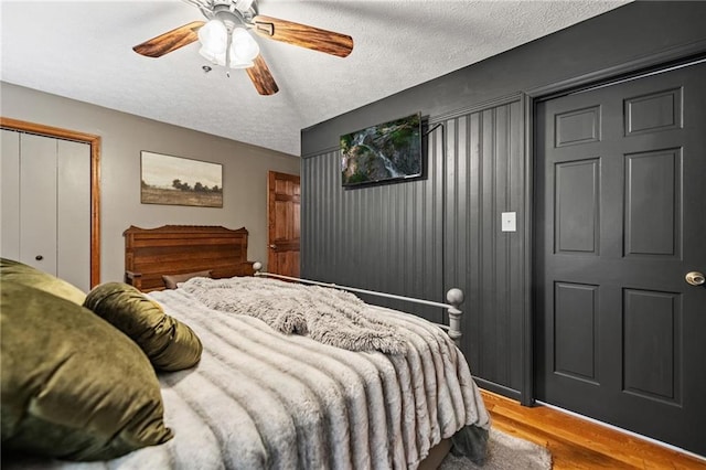 bedroom with a textured ceiling, ceiling fan, a closet, and light wood-style flooring