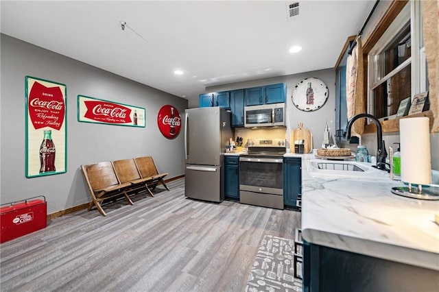 kitchen featuring blue cabinets, stainless steel appliances, a sink, visible vents, and light countertops