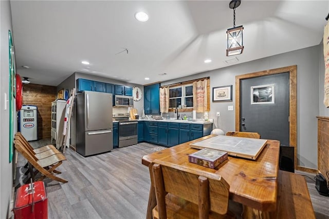 kitchen featuring light wood finished floors, appliances with stainless steel finishes, blue cabinets, light countertops, and pendant lighting