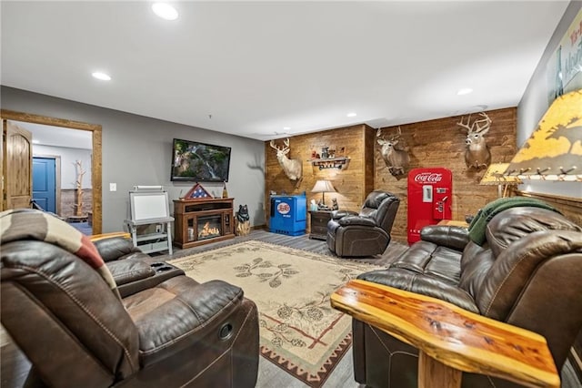 living area with a glass covered fireplace, wooden walls, and recessed lighting