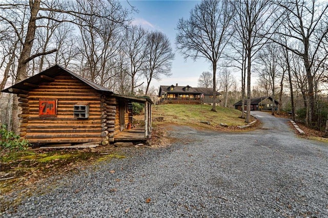 view of home's exterior with gravel driveway and log siding